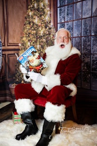 a santa claus sitting in front of a christmas tree