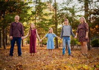 a family is holding hands in a wooded area